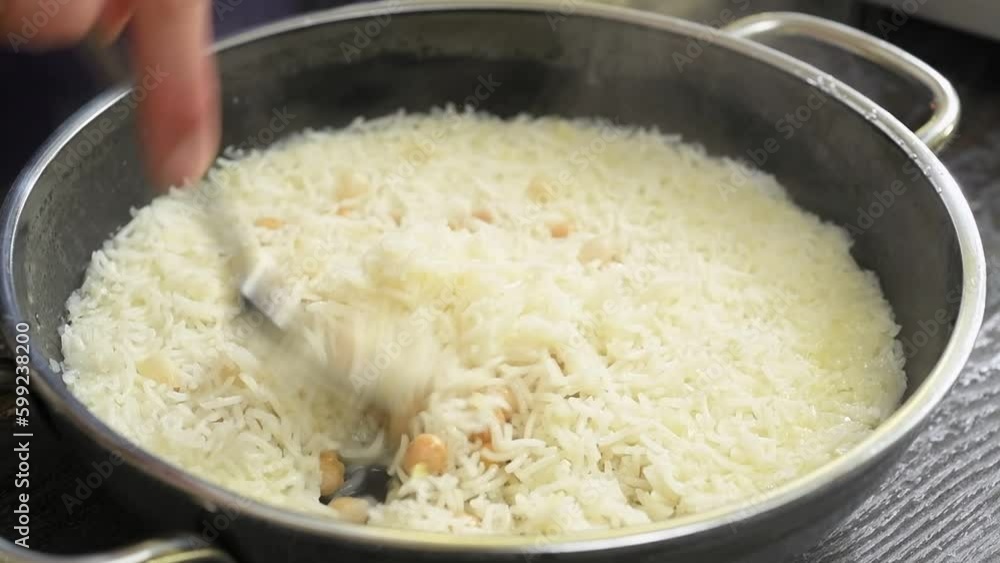 Stirring rice with chickpeas in the frying pan.
Stirring rice with chickpeas in the frying pan.