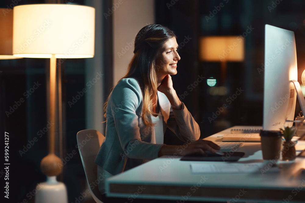 Total dedication at all hours. a young businesswoman using a computer during a late night at work. Total dedication at all hours. a young businesswoman using a computer during a late night at work.