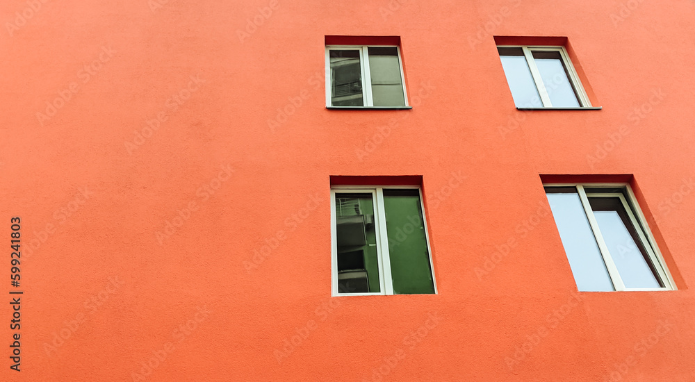 Red wall exterior with four modern glass windows. Deep orange stucco wall paint.Copy space.