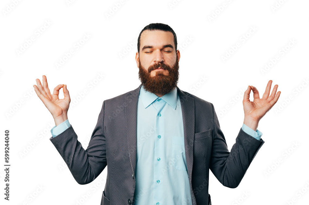 Relaxed bearded man wearing a jacket is staying in mudra pose in a studio over white background. Relaxed bearded man wearing a jacket is staying in mudra pose in a studio over white background.