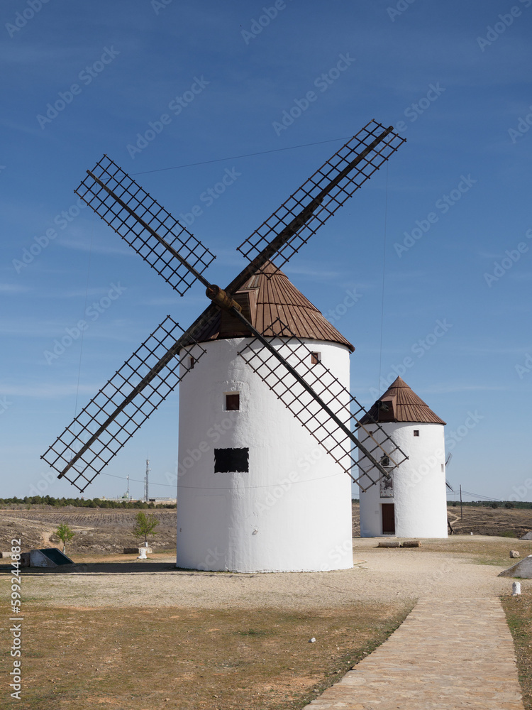 Two windmills on La Mancha land. Sunny day and blue sky with clouds. Mota del cuervo.