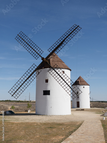 Two windmills on La Mancha land. Sunny day and blue sky with clouds. Mota del cuervo.