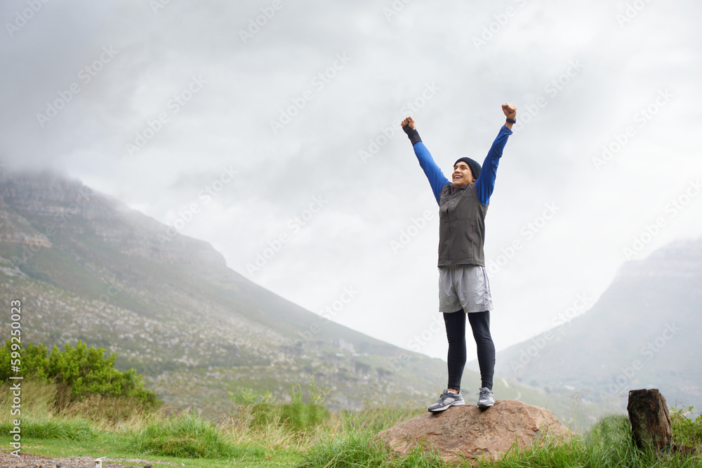 Feeling fit and free. A young man celebrating at the top of a mountain after reachin. Feeling fit and free. A young man celebrating at the top of a mountain after reachin.
