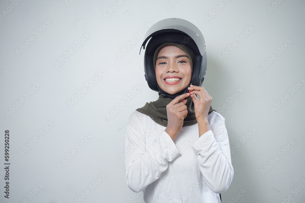 Smiling young Asian muslim woman using motorcycle helmet isolated on white background Smiling young Asian muslim woman using motorcycle helmet isolated on white background