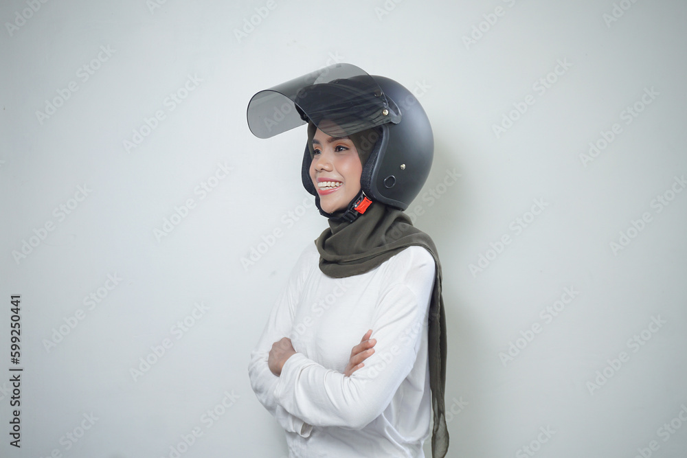 Smiling young Asian muslim woman using motorcycle helmet isolated on white background Smiling young Asian muslim woman using motorcycle helmet isolated on white background