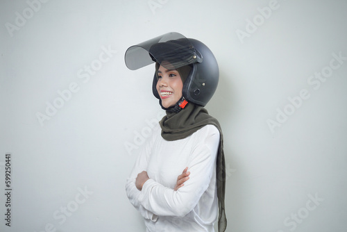 Smiling young Asian muslim woman using motorcycle helmet isolated on white background