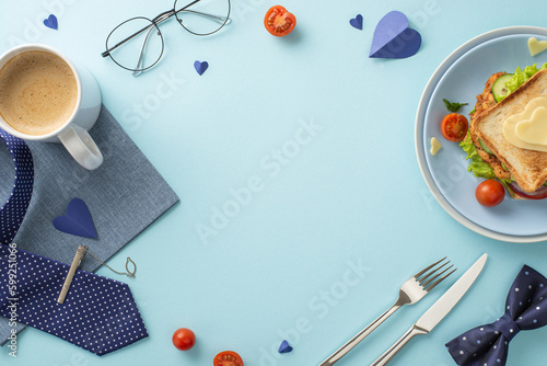Show Dad how much you care with a breakfast surprise. Top view of a veggie sandwich, cutlery, coffee cup, napkin, necktie, glasses, bow-tie, on pastel blue background with an empty frame for text
