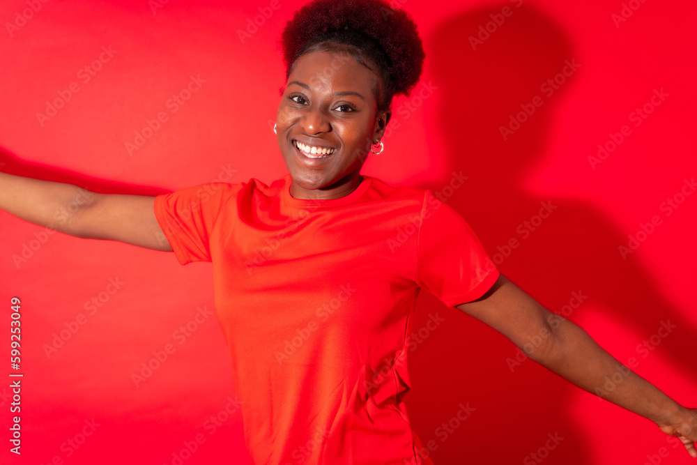 Young african american woman isolated on a red background smiling and dancing, studio shoot Young african american woman isolated on a red background smiling and dancing, studio shoot