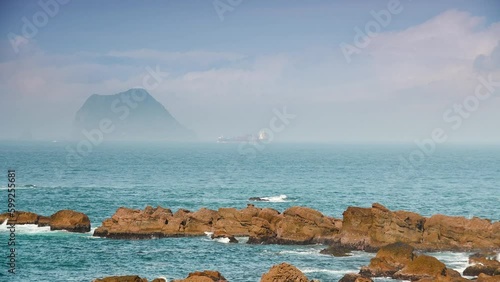 A small island shrouded in mist, blue sea and blue sky. View of Keelung Island from Wanli Beach in New Taipei City. Taiwan. photo