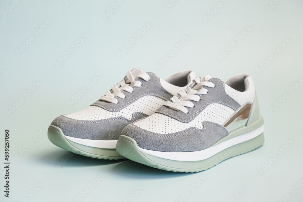 Sneakers for everyday use on a pale green background. Pair of unisex leather athletic boots with suede overlays and water-repellent fabric. Summer footwear for sports, recreation, travel.