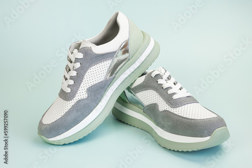 Sneakers for everyday use on a pale green background. Pair of unisex leather athletic boots with suede overlays and water-repellent fabric. Off-season shoes for sports, recreation, travel.