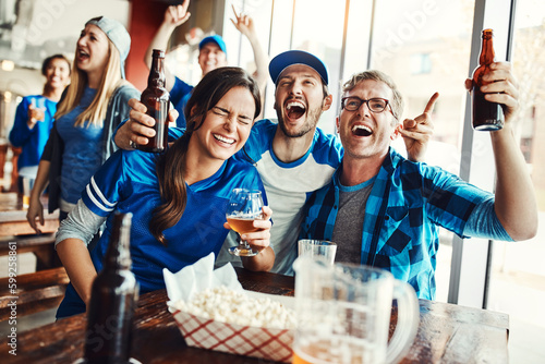 Fototapeta Naklejka Na Ścianę i Meble -  The bar is where its all going down. a group of friends cheering while watching a sports game at a bar.