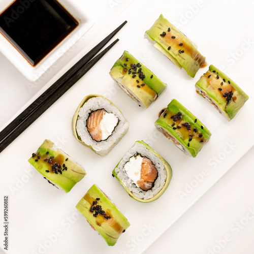 Sushi plate on white background, rolls set with cucumber on white background from above. Top view of traditional japanese cuisine. Asian food with chopsticks design.