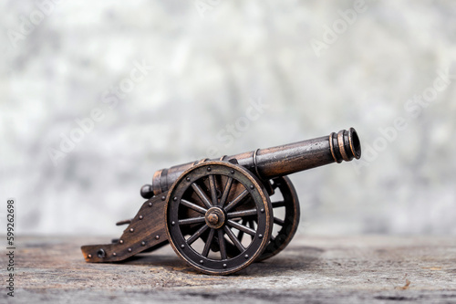Fotografering Ancient cannon on steel wheels with wall background retro style.
