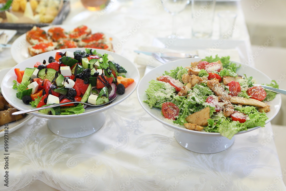 Caesar and Greek salads on the festive table Caesar and Greek salads on the festive table
