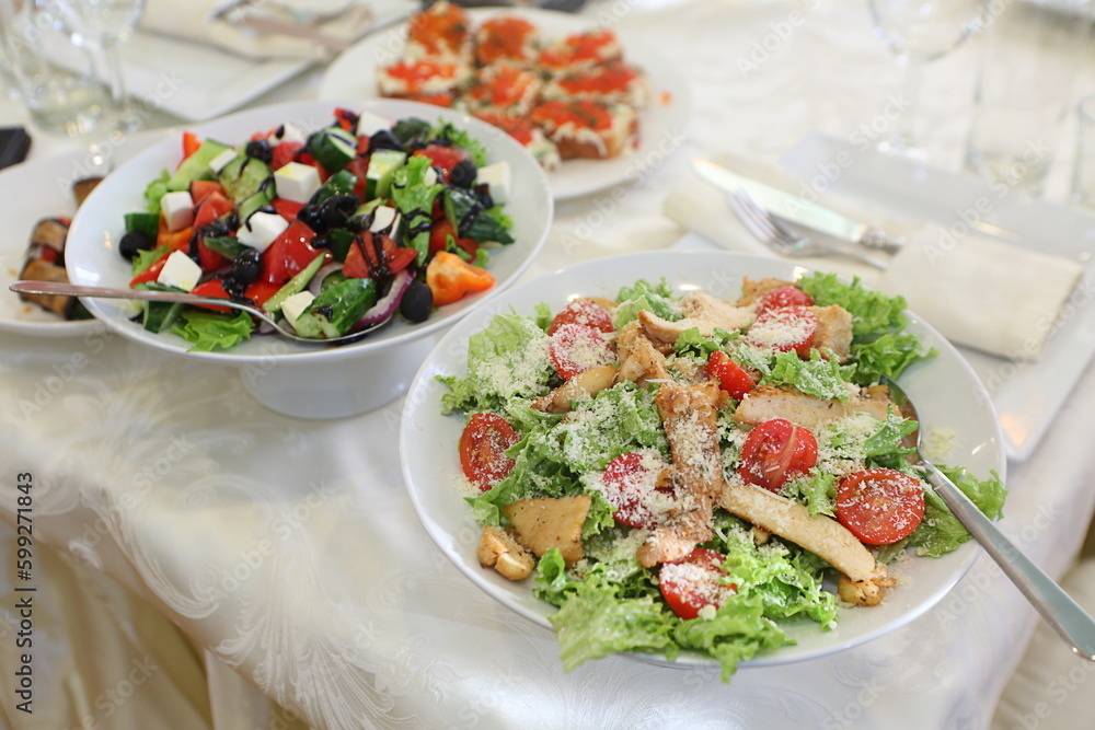 Caesar and Greek salads on the festive table Caesar and Greek salads on the festive table
