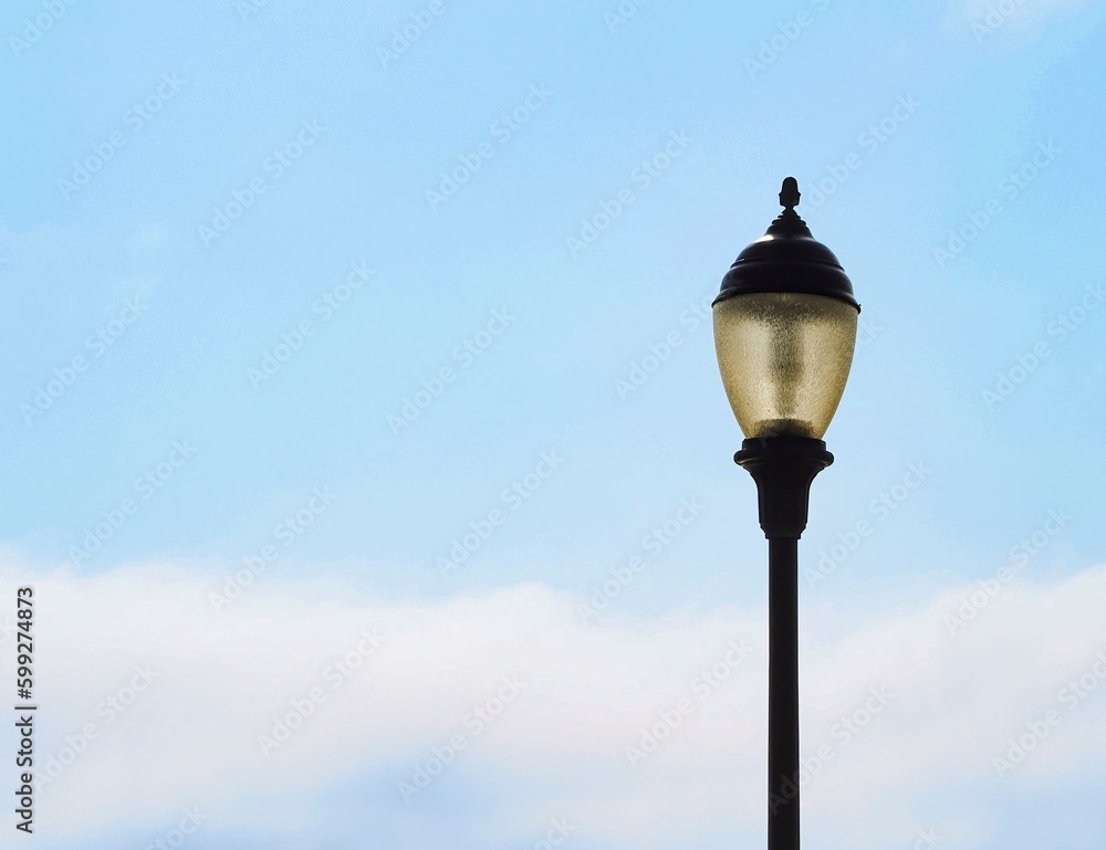 Old-fashioned lamp post, street light, light pole in daytime, with glass lantern, against light blue sky with clouds, copy space. Old-fashioned lamp post, street light, light pole in daytime, with glass lantern, against light blue sky with clouds, copy space.