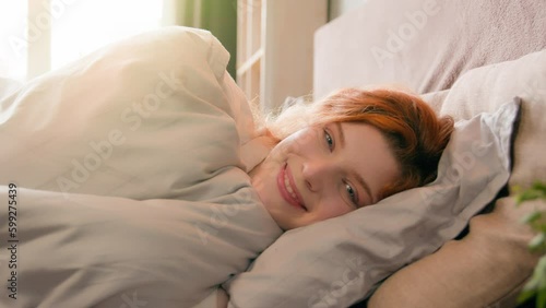 Sleepy beautiful woman waking up lying in comfortable white bed smiling toothy happy smile carefree attractive girl female early good morning relax in cozy bedroom lazy lady awake after sleep at home photo