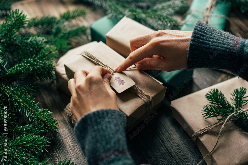 © Ilona - Unrecognizable woman wraps a Christmas present with craft paper. © Ilona - Unrecognizable woman wraps a Christmas present with craft paper.