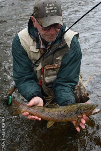 Angler with trout in stream 