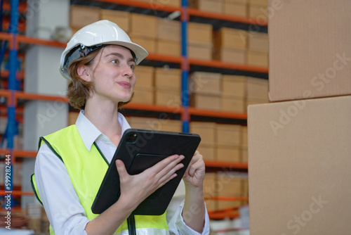 A female manager is checking inventory inside a warehouse.