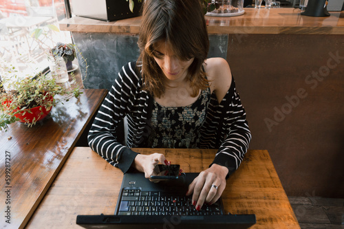 top view young latin freelance transgender woman working with her laptop inside a restaurant photo