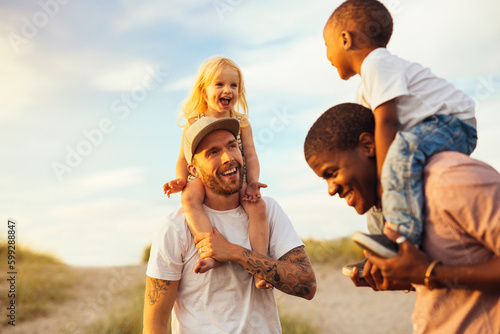 Two fathers giving piggyback ride to daughters (2-3)
