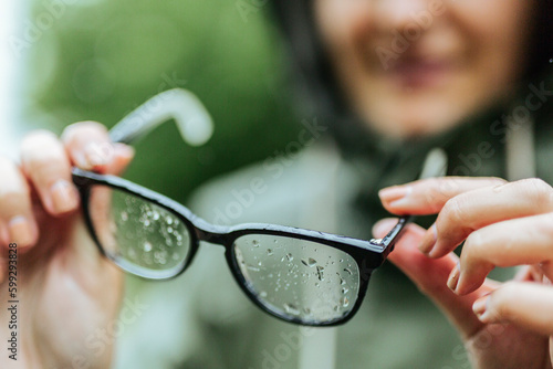Close-up of woman holding eyeglasses in rain photo