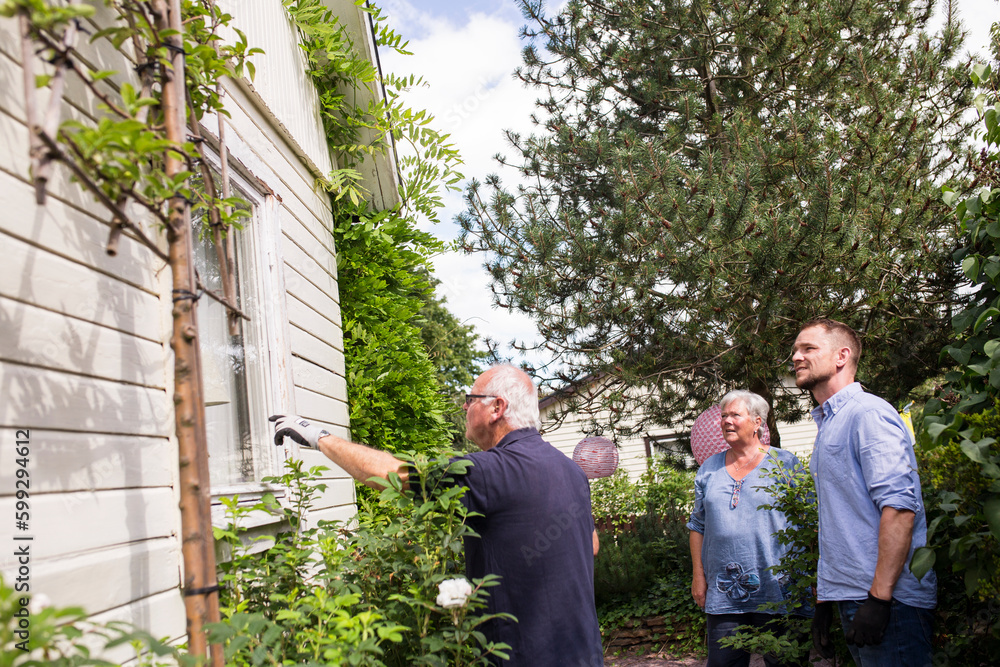 Parents with adult son working in garden Parents with adult son working in garden