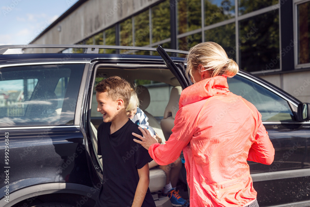 Mother with sons (10-11, 12-13) getting out of car Mother with sons (10-11, 12-13) getting out of car