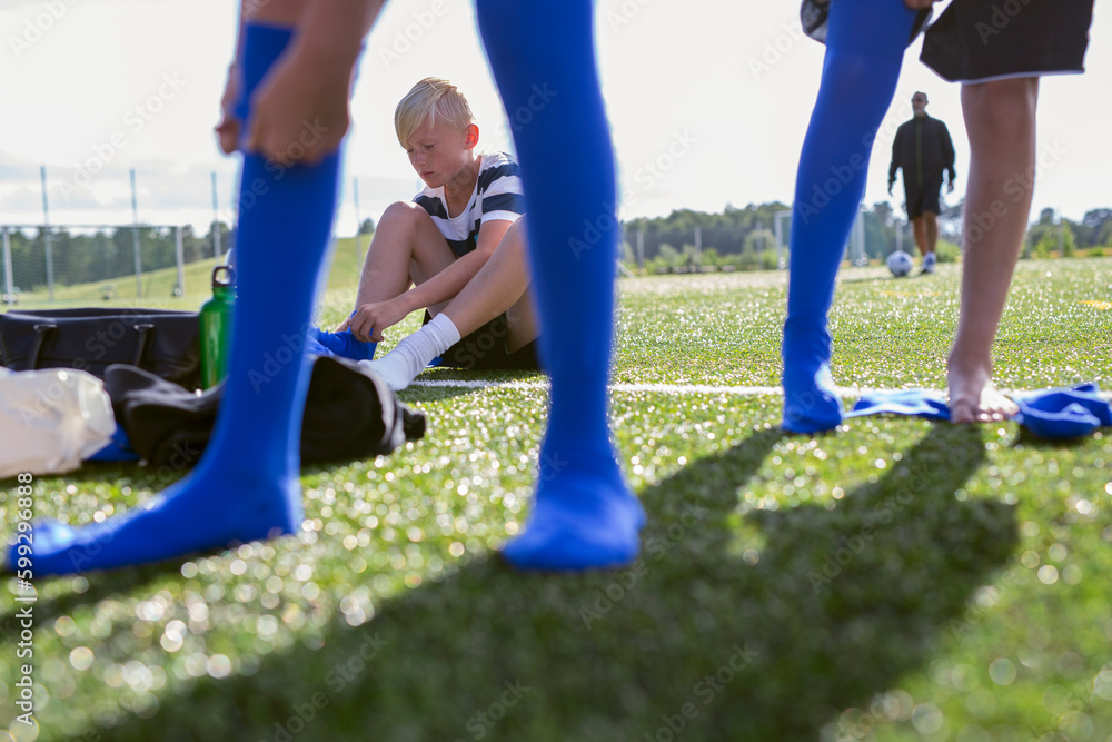 Boys (10-11) putting on soccer socks Boys (10-11) putting on soccer socks