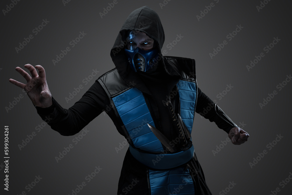 Ice stealth killer dressed in mask and hood posing against grey background.