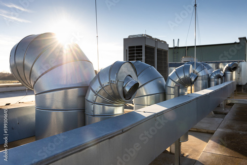 External unit of commercial air conditioning and ventilation system installed on industrial building roof. Exhaust vent on flat factory rooftop photo