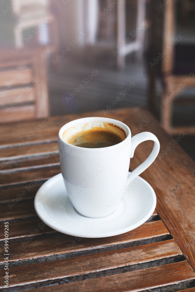Hot black coffee in a white mug on a wooden table.
