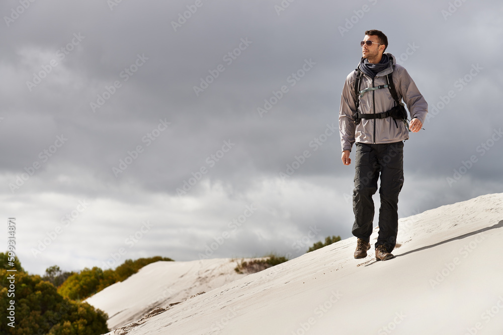 He handles these hills like a seasoned hiker. a young male hiker walking along the sand dunes. He handles these hills like a seasoned hiker. a young male hiker walking along the sand dunes.