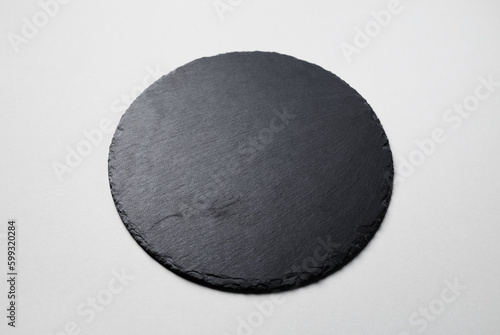 Black round stone slate plate on gray paper background.