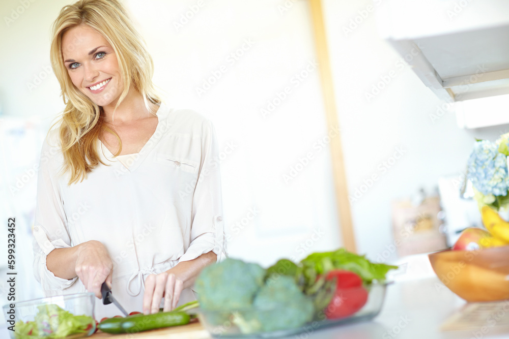 Making a tasty salad. Attractive young blonde woman smiling while chopping fresh vegetables at home. Making a tasty salad. Attractive young blonde woman smiling while chopping fresh vegetables at home.