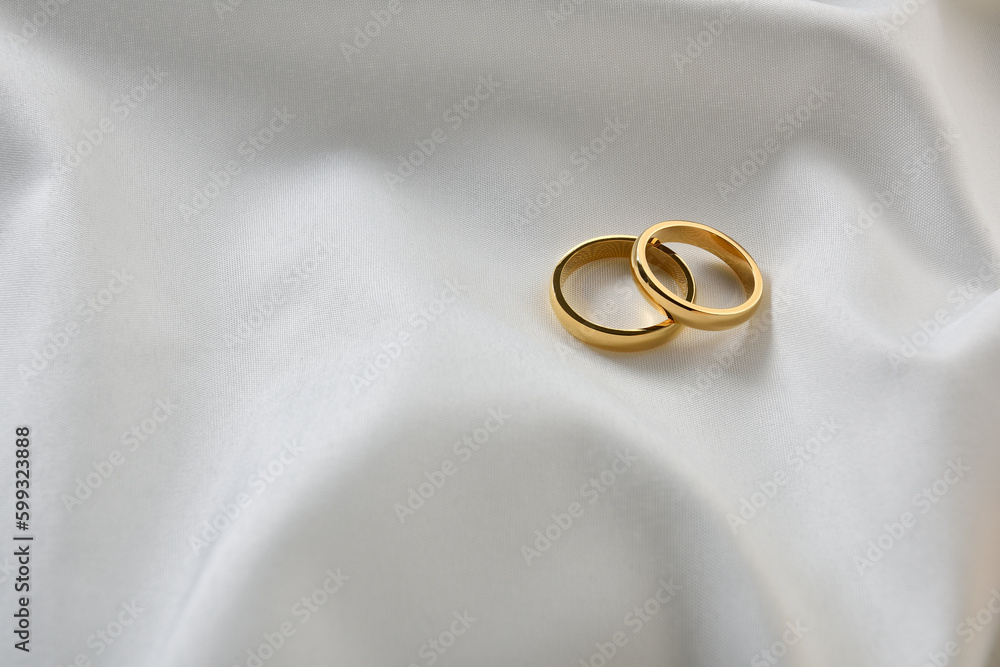 Gold rings on white shiny fabric top view Gold rings on white shiny fabric top view