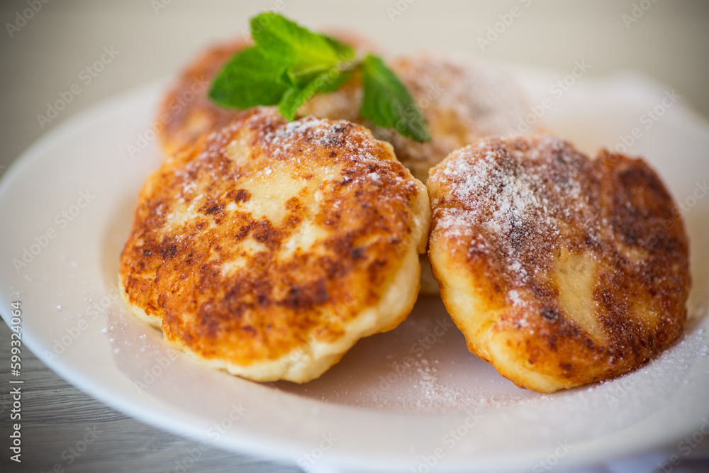 Sweet cooked cheesecakes in powdered sugar in a plate Sweet cooked cheesecakes in powdered sugar in a plate