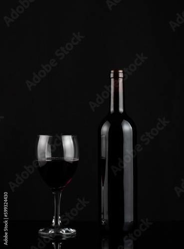 Red wine bottle and glass on dark background