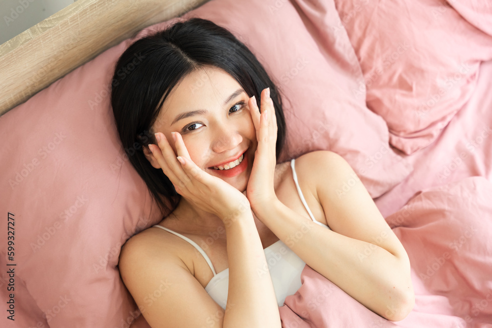 Fototapeta premium Portrait of a beautiful and playful asian girl in bed in the morning