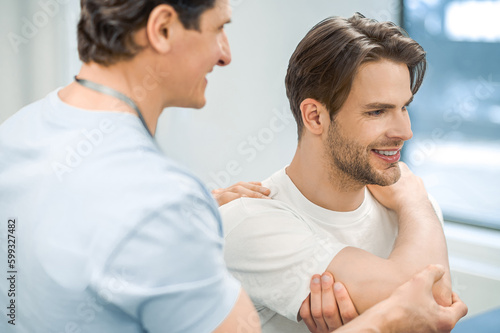 Manual therapist helping patient to work out the shoulder joint