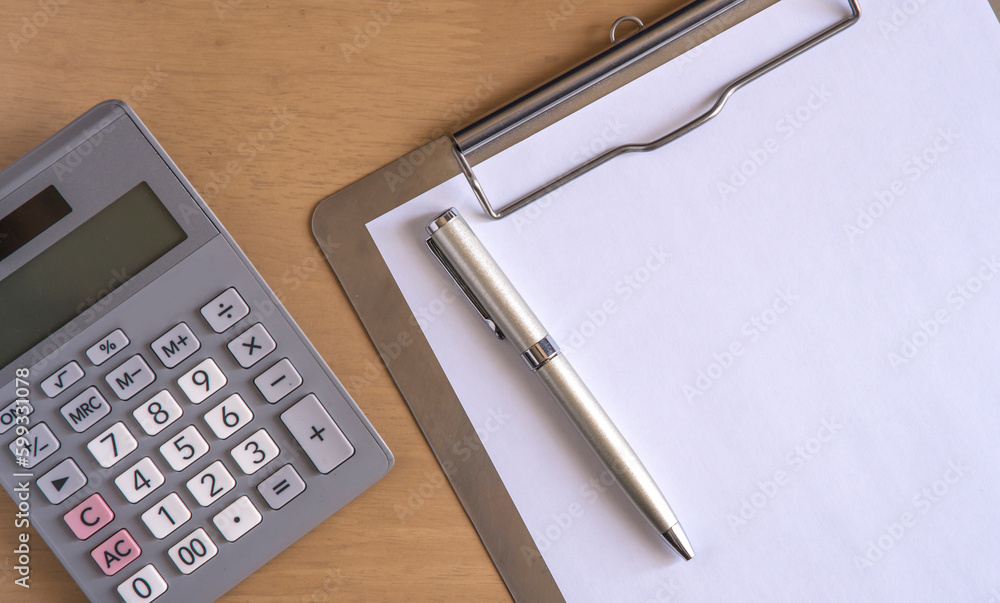 Calculator , pen and clipboard with blank paper on the desk . Calculator , pen and clipboard with blank paper on the desk .