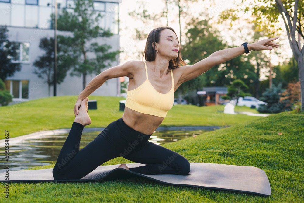 Caucasian adult woman in sportswear doing leg stretching in the city park. Healthy lifestyle, sport. Positive person. Fitness woman. Body positive. Healthy Caucasian adult woman in sportswear doing leg stretching in the city park. Healthy lifestyle, sport. Positive person. Fitness woman. Body positive. Healthy