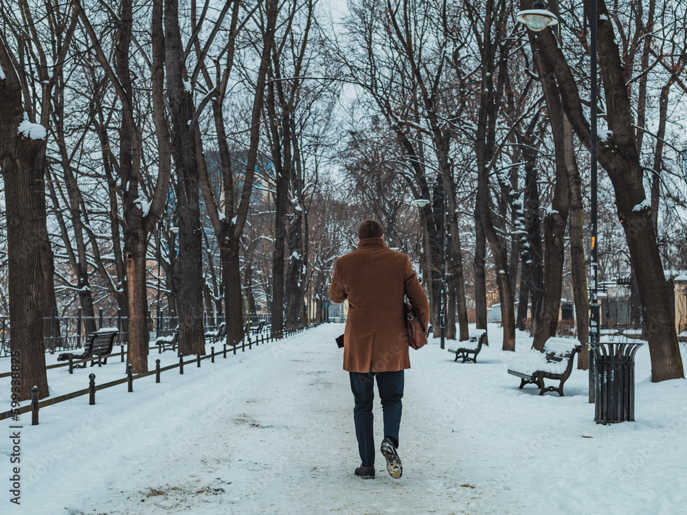 man in coat on city park path in winter man in coat on city park path in winter