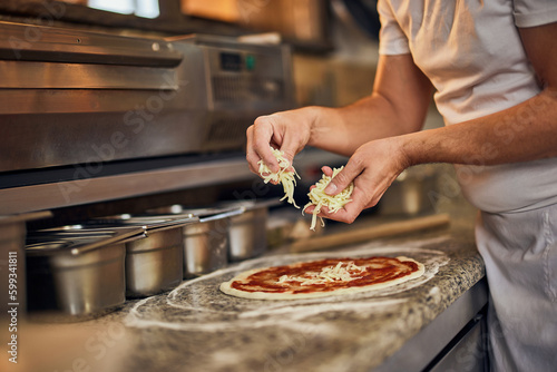 Close-up of a male pizza master hands, making delicious pizza, putting cheese.