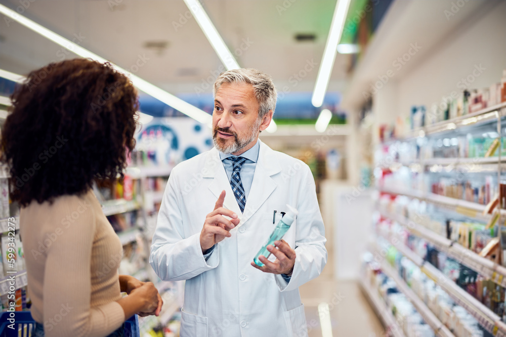 Obraz premium A senior male pharmacist is talking with a female customer about some product in the apothecary.