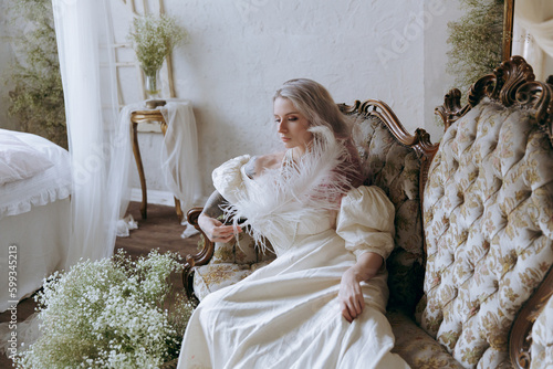 A luxurious girl with a beautiful make-up and hairstyle in a vintage vintage dress woke up in the morning in bed and sits on the sofa at the piano and poses as a model