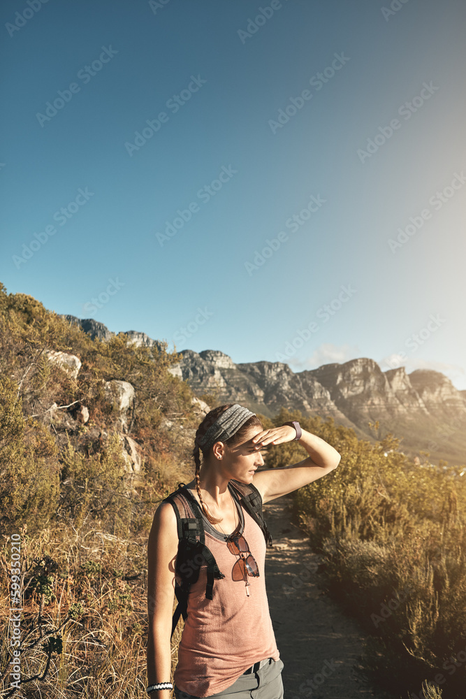 Naklejka premium Exploring the lands near and far. a young woman out on a hike through the mountains.