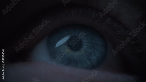 Starry sky reflected in an opening blue human eye. Macro close up. Slow motion. 